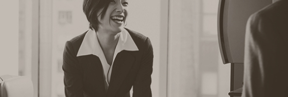 Cropped image of female standing on desk, smiling. 